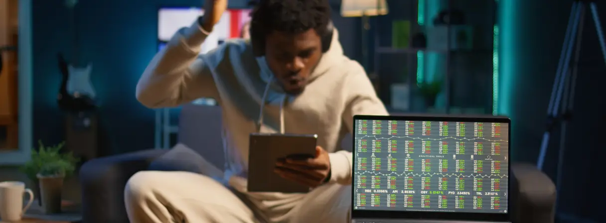 A man in a hoodie sits on a couch plays online casino in a tablet